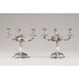 A pair of two branch candelabraPortuguese silver High relief foliage decoration on a circular ra