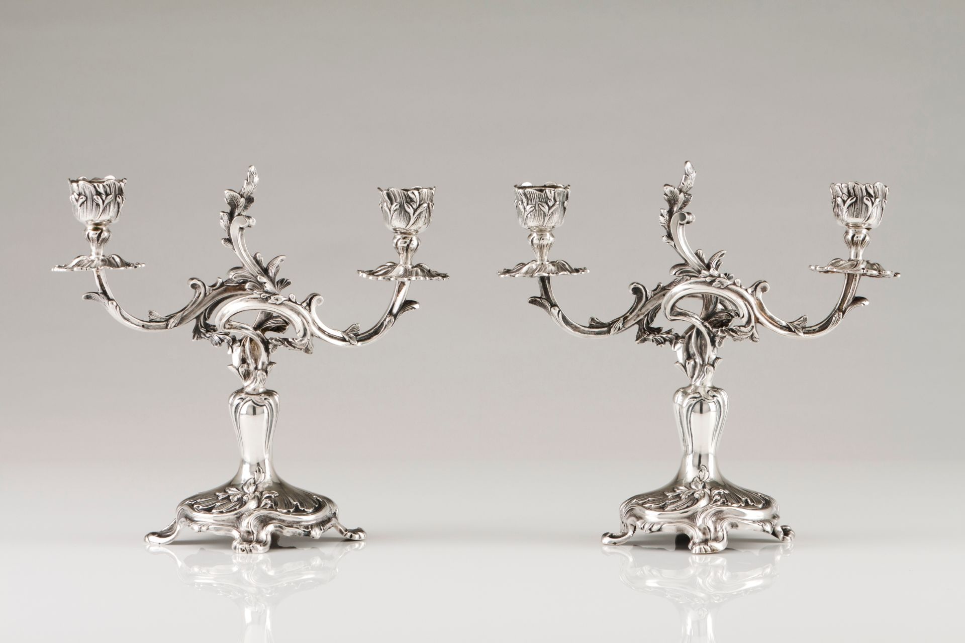 A pair of two branch candelabraPortuguese silver High relief foliage decoration on a circular ra