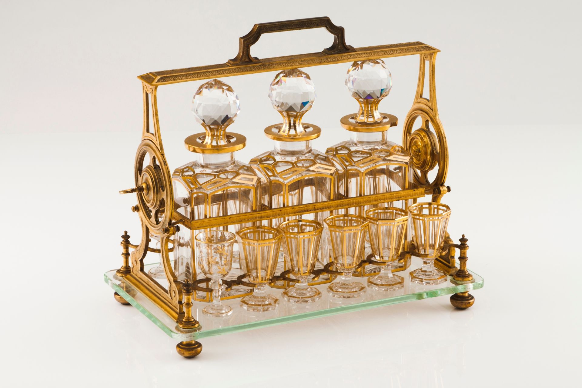 A Baccarat tantalusGilt bronze stand with glass base and bottle lock Three bottles and 12 gilt d