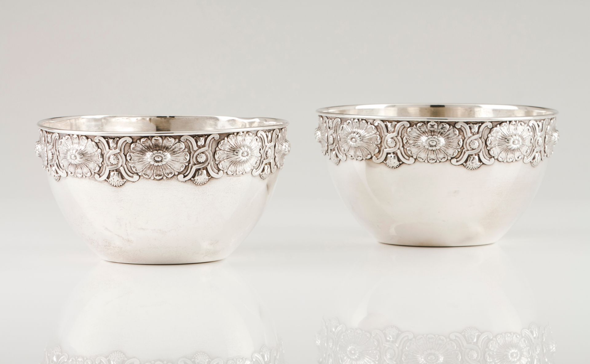 A pair of bowlsPortuguese silver Plain body of raised wide band with medallions and floral and f