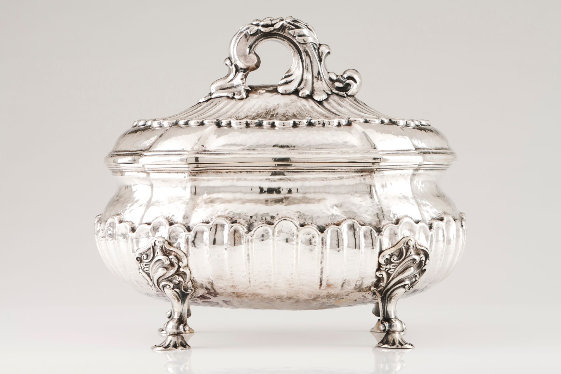 A large tureen and coverPortuguese silver Oval shaped body, hammered and part fluted, on 4 sleep