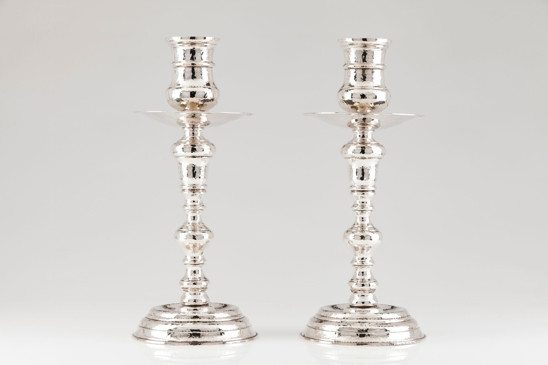 A pair of large candle standsPortuguese silver Turned and hammered decoration to base, shaft and