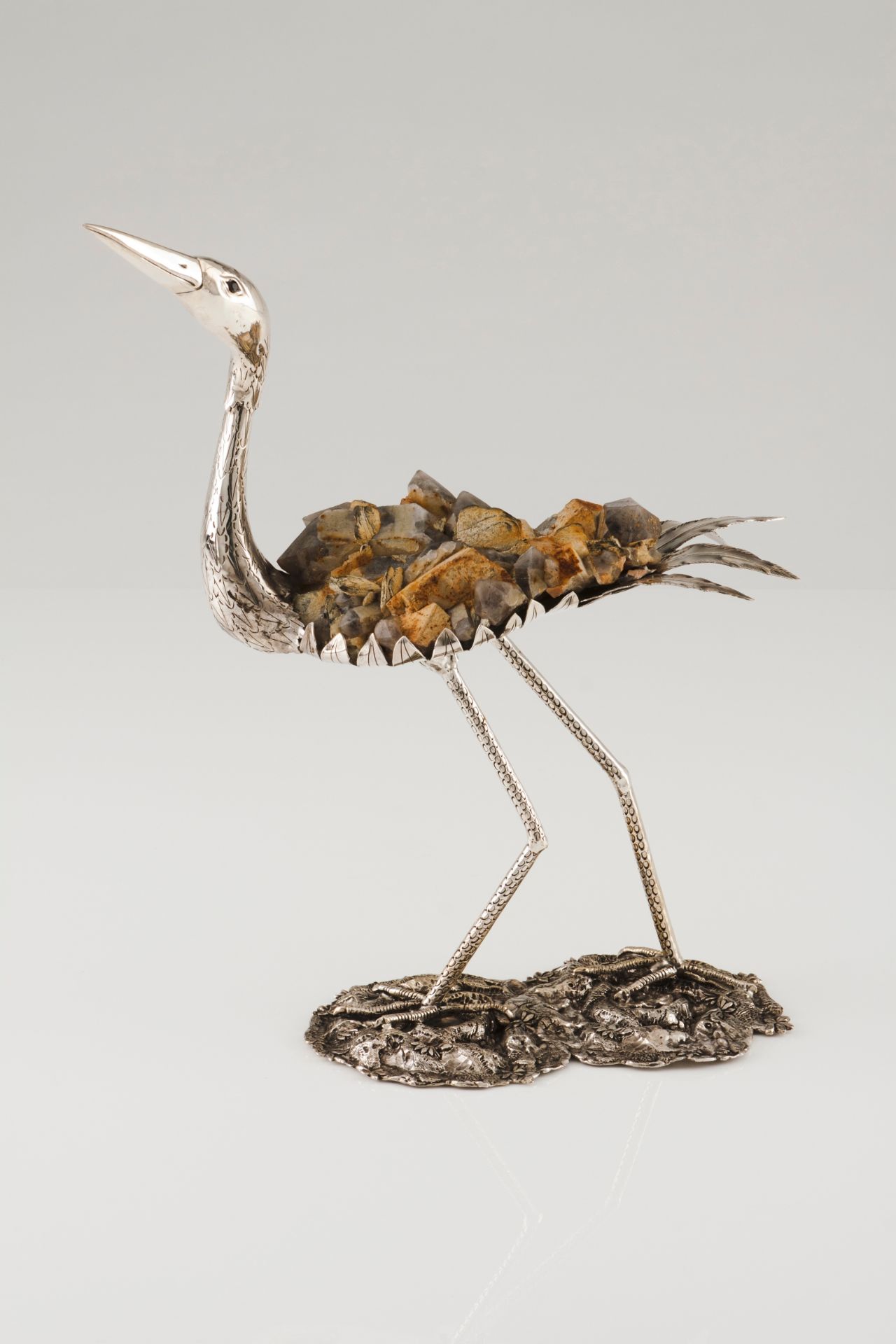 A long legged birdSilver and stone composite Moulded, scalloped and engraved sculpture on a natu