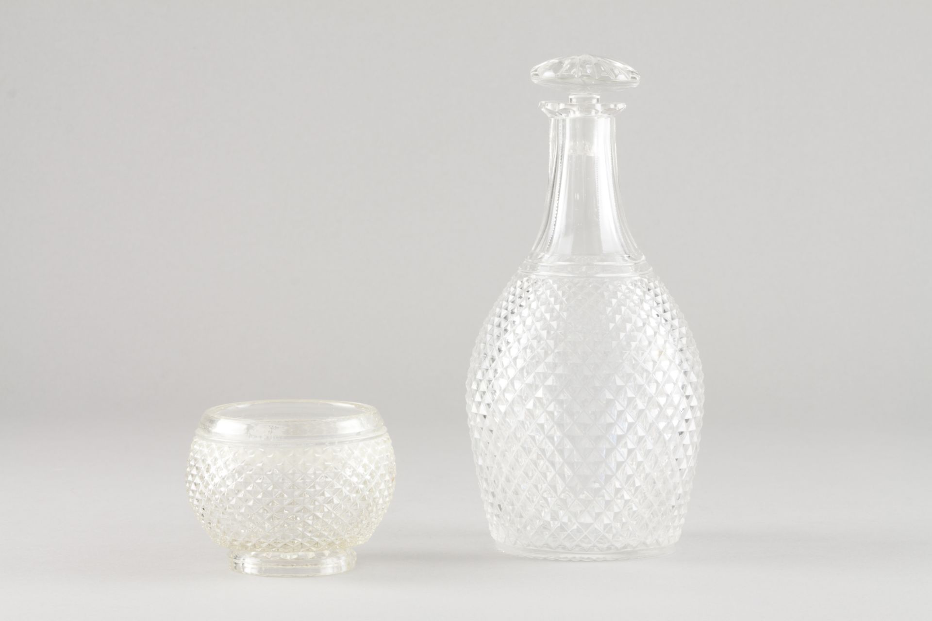 A bottle and beakerMoulded crystal Height: 24 cm (bottle) Height: 8 cm (bowl)