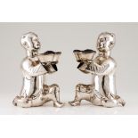 A pair of Luiz Ferreira laughing boysSilver Moulded sculptures holding votive offering bowls