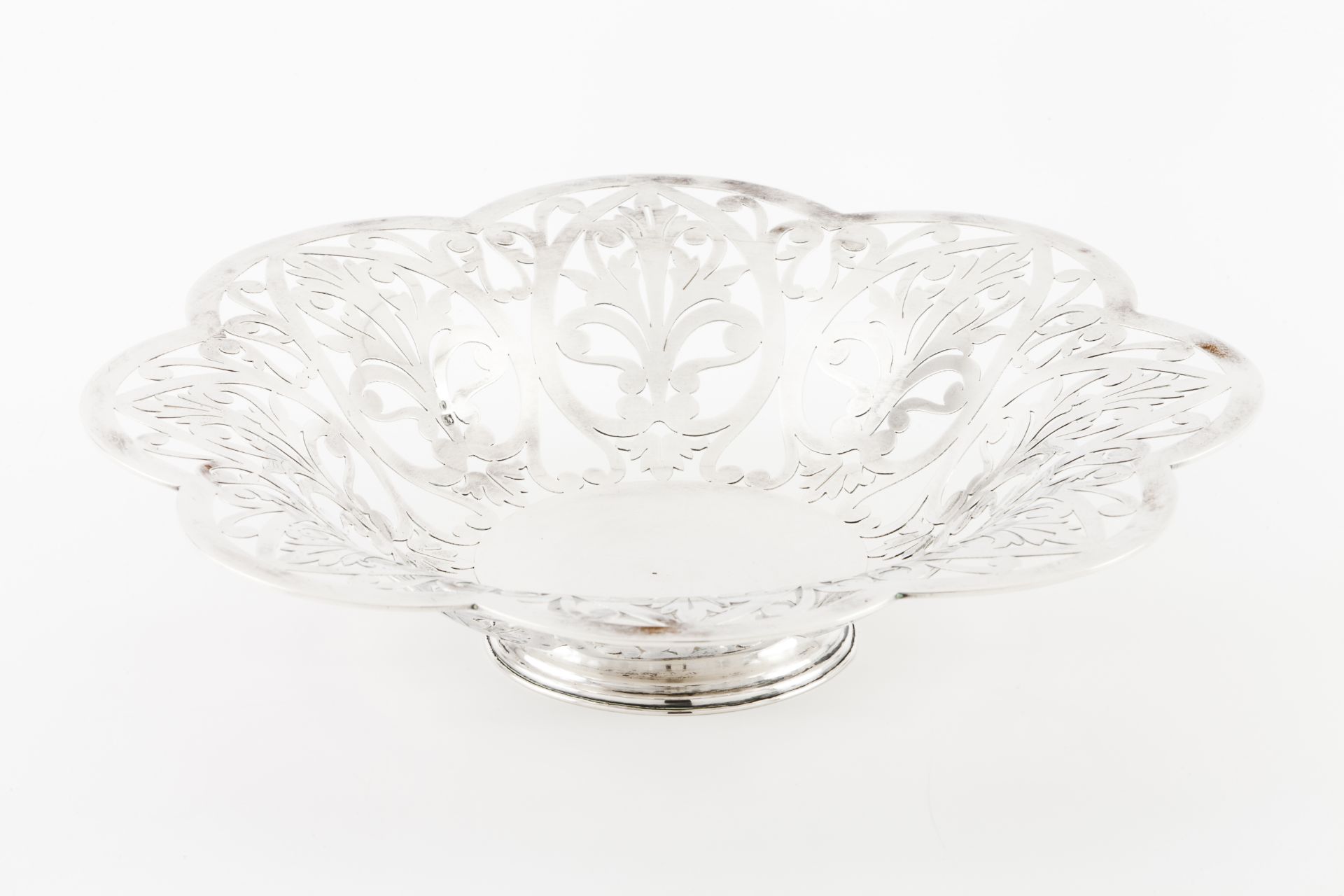 A footed fruit bowlPortuguese silver Plain centre of scalloped and pierced lip with stylised foliage