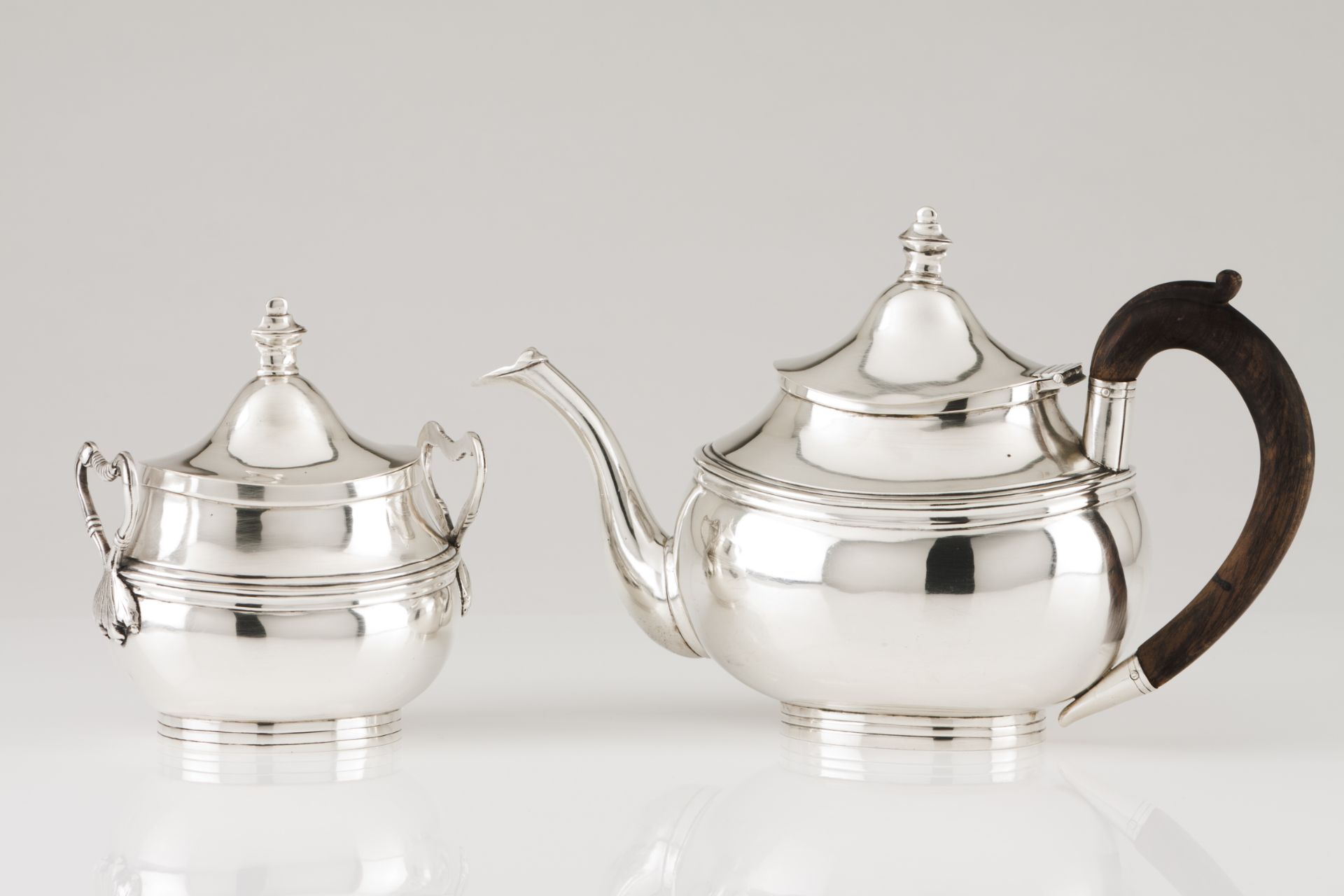 A teapot and sugar bowlPortuguese silver Oval shaped body of engraved frieze and flattened urn lid