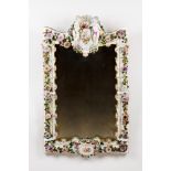 A wall mirrorEuropean Meissen style porcelain frame Raised and polychrome floral decoration Crest