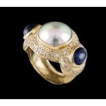 A ring Gold Set with one Mabe pearl flanked by 2 cabochon cut sapphires (ca. 8x6 mm) and small