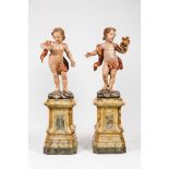 A pair of puttiCarved, polychrome and gilt wooden sculptures One holding flower bouquet the other