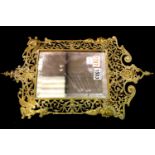 19th century bevelled wall mirror, the pierced brass frame decorated with masks and mythical