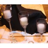 Set of three amethyst coloured glass graduated glass candle holders, tallest H: 70 cm. Not available