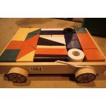 A wooden pull along trolley containing coloured childrens building blocks. Not available for in-