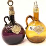 Two blown glass carafes with white metal mounts and labels, to measure 25 cm including stopper. P&