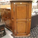 A substantial Georgian oak wall hanging corner cupboard with panelled single door and four