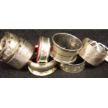 Five hallmarked silver napkin rings, a silver plate example and a silver plate bottle collar,