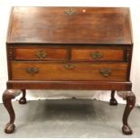 A 19th century walnut fall-front bureau having a fitted interior, three drawers and a heavily carved