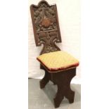 An early oak hall chair, the backrest carved with an armorial of griffins and a shield, with