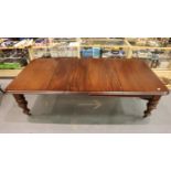 A Victorian mahogany wind out extending dining table with three additional leaves, raised on