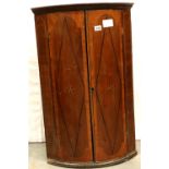 George III walnut barrel front wall hanging cupboard, enclosing three shelves, the facia inclaid