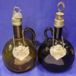 Two blown glass carafes with white metal mounts and labels, to measure 25 cm including stopper.