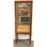 An early 20th century oak glazed shop cabinet by Ashton, Leach and Cumberbirch Ltd, Rochdale, with