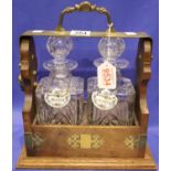 Oak tantalus with brass mounts, two crystal decanters with two china alcohol labels (no key). Not