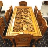A deeply carved substantial Oriental hardwood dining table with plate glass top displaying figures