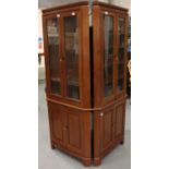 A pair of floor standing corner cupboards, each having a single glazed door with internal shelves,