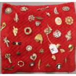 Collection of mixed brooches including stone set examples, displayed on a cushion, 41 x 38 cm. P&P
