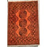 Red ground woollen fringed rug with three decorative panels, 100 x 150 cm. Not available for in-