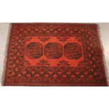 Red ground woollen fringed rug with three decorative panels, 100 x 150 cm. Not available for in-