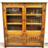 A 20th century Old Charm oak bookcase with two glazed doors, two shelves and two carved cupboard