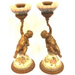 Pair of gilt metal and ceramic garnitures in the form of putti holding torches, each H: 25 cm. P&P