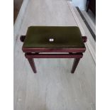 A modern adjusting piano stool upholstered in green