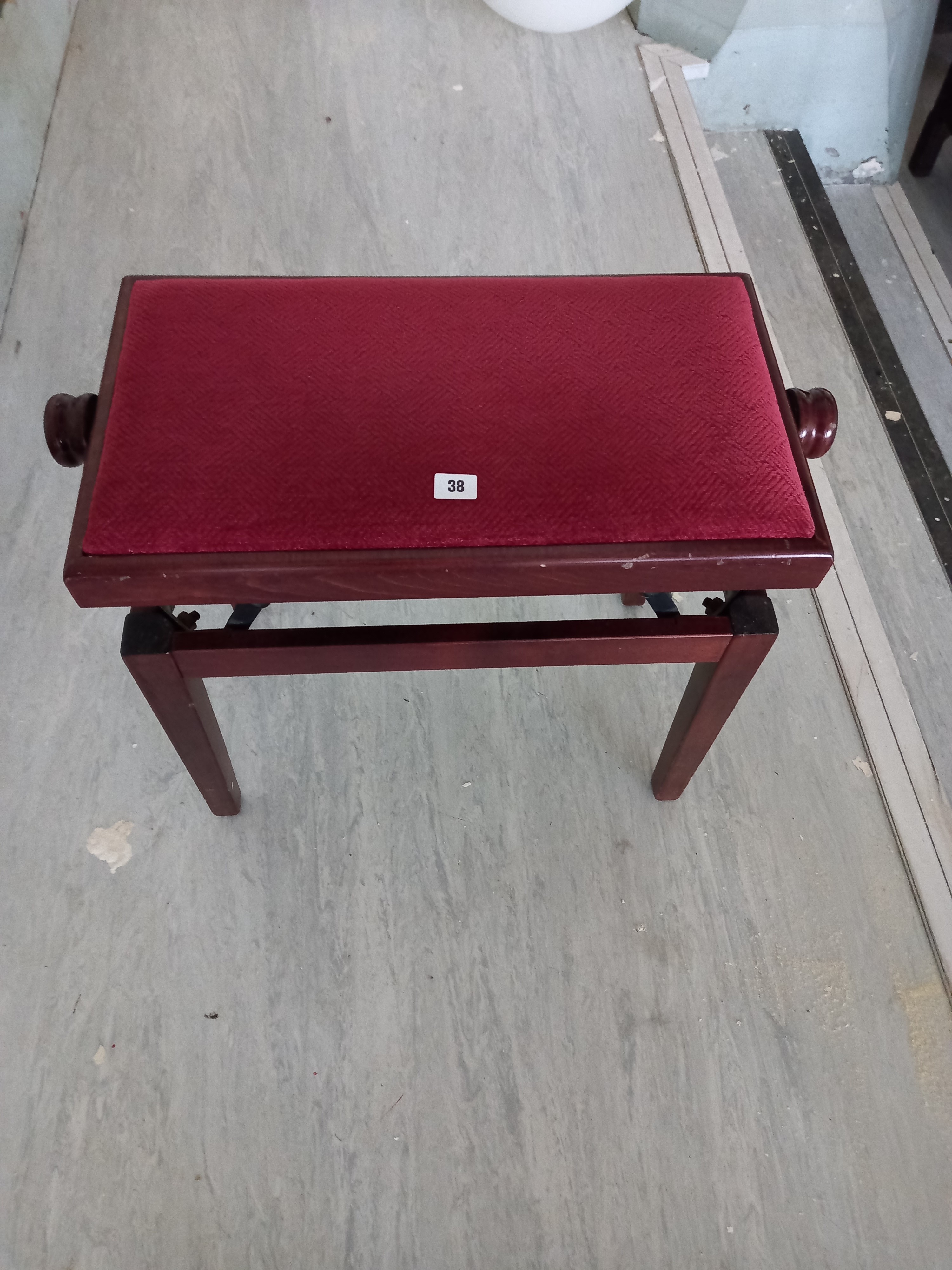 A modern adjusting piano stool upholstered in Red