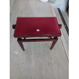 A modern adjusting piano stool upholstered in Red