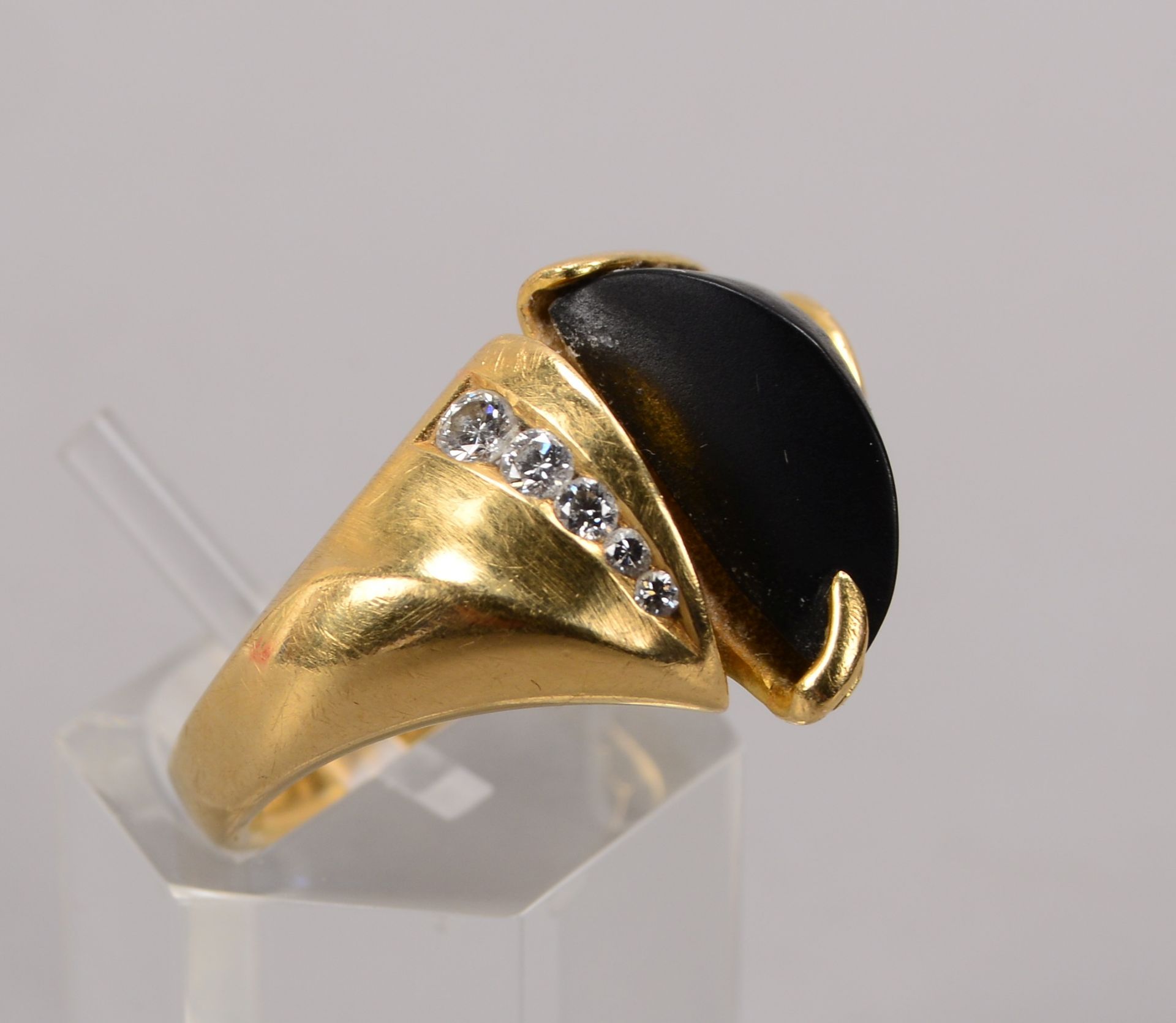 Ring (Goldschmiedearbeit), 750 GG, besetzt mit einzelnem mattiertem Onyx, sowie mit 5x kleinen Brill
