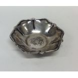 A small silver dish decorated with central crest.