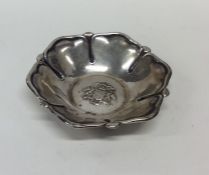 A small silver dish decorated with central crest.