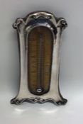 A cased silver thermometer with shaped decoration.