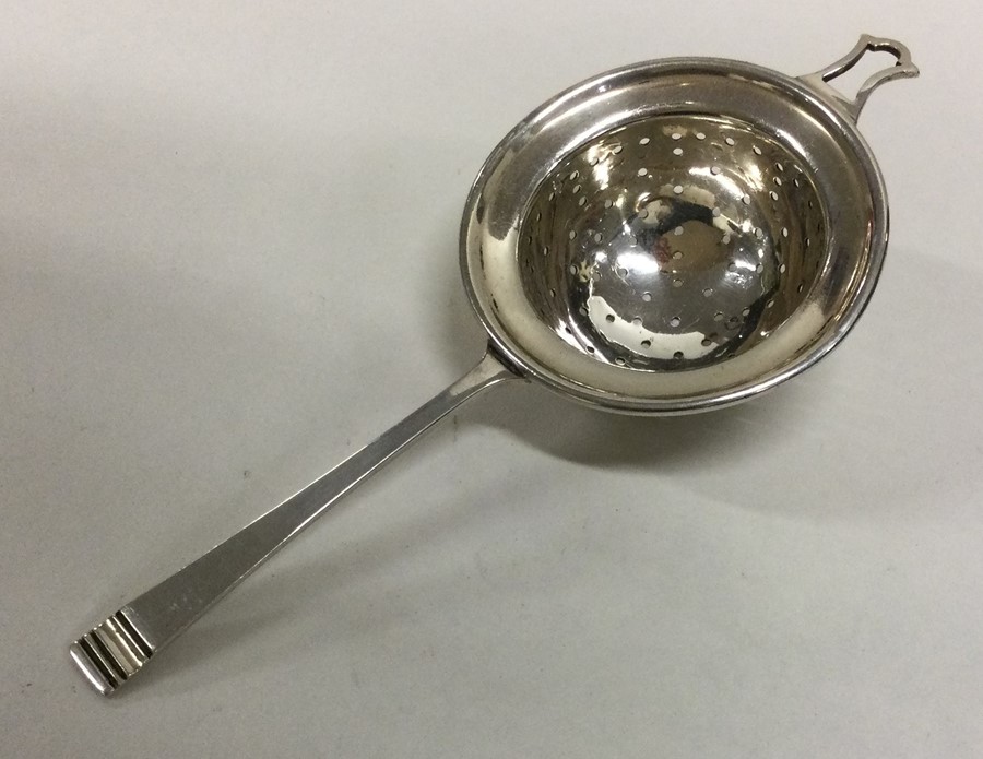 A stylish silver tea strainer with tapering handle