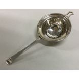 A stylish silver tea strainer with tapering handle