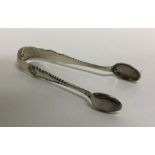 A pair of silver sugar tongs with scroll decoratio