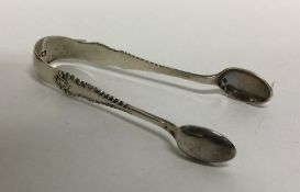 A pair of silver sugar tongs with scroll decoratio