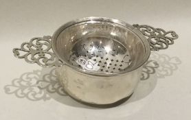 An Edwardian silver tea strainer on stand with pie