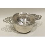 An Edwardian silver tea strainer on stand with pie