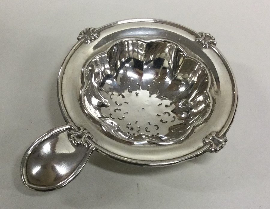 An attractive silver tea strainer with plain thumb