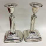 A pair of Edwardian silver candlesticks on square