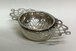 An Edwardian silver tea strainer on stand with pie